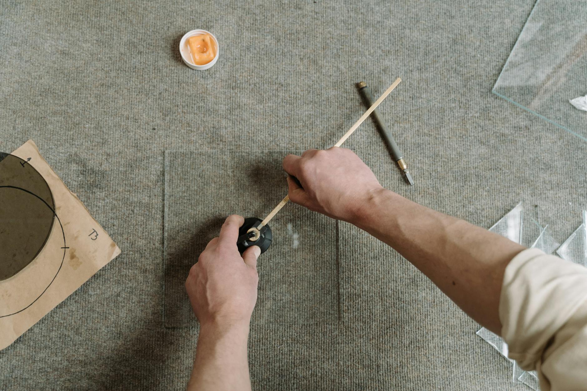 Ręce rzemieślnika precyzyjnie tnące szkło na stole warsztatowym