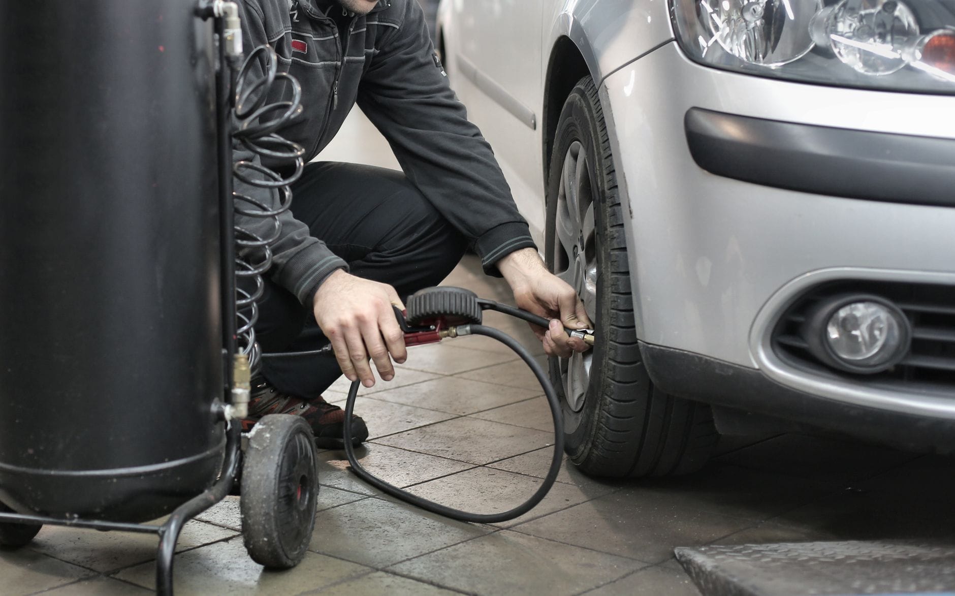 Jak przygotować samochód do długiej trasy: przegląd zawieszenia, hamulców i ogumienia Mechanik sprawdza ciśnienie w oponie auta przed dłuższą trasą