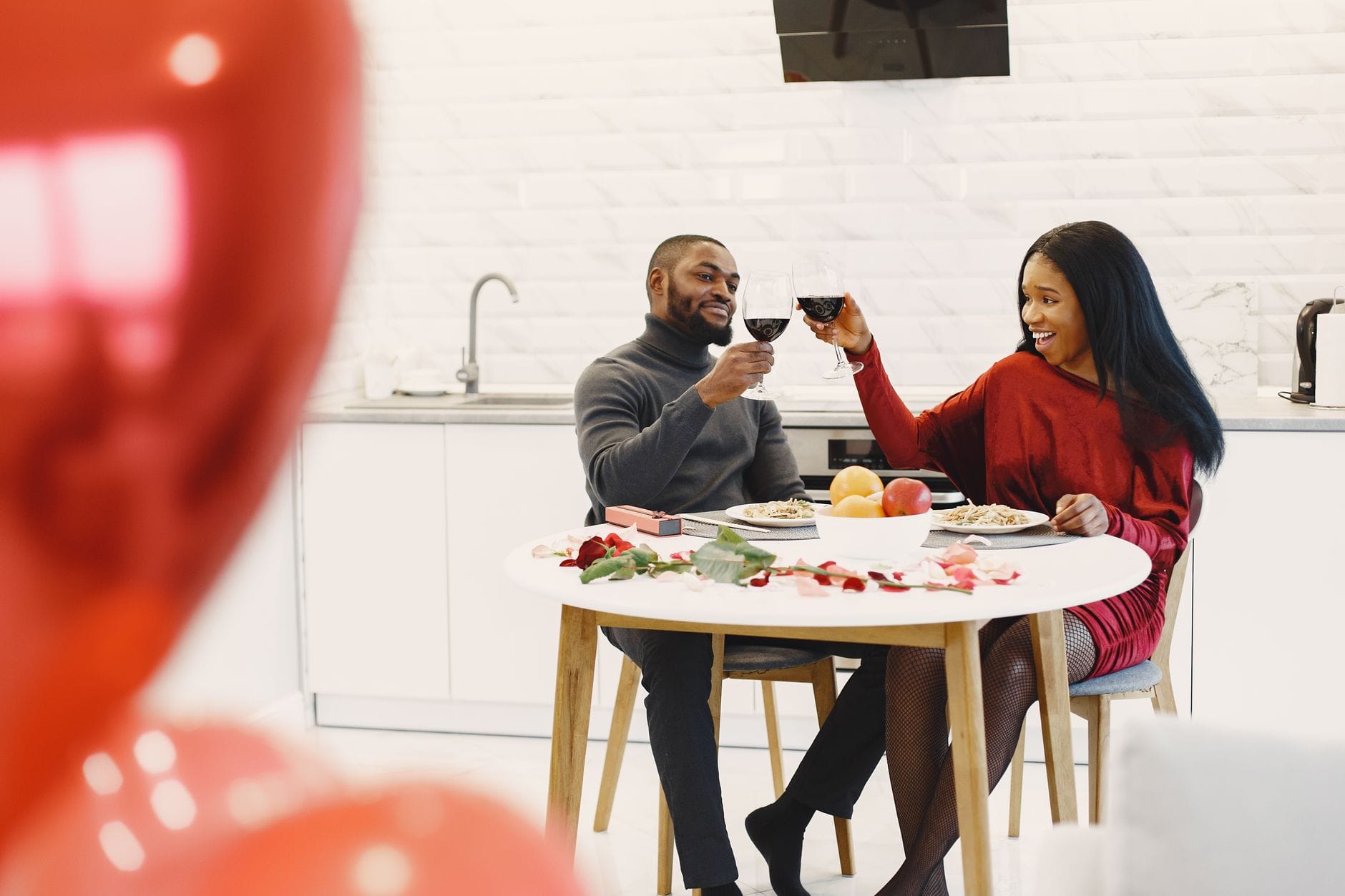 Para przy świecach je romantyczną kolację z winem i różami