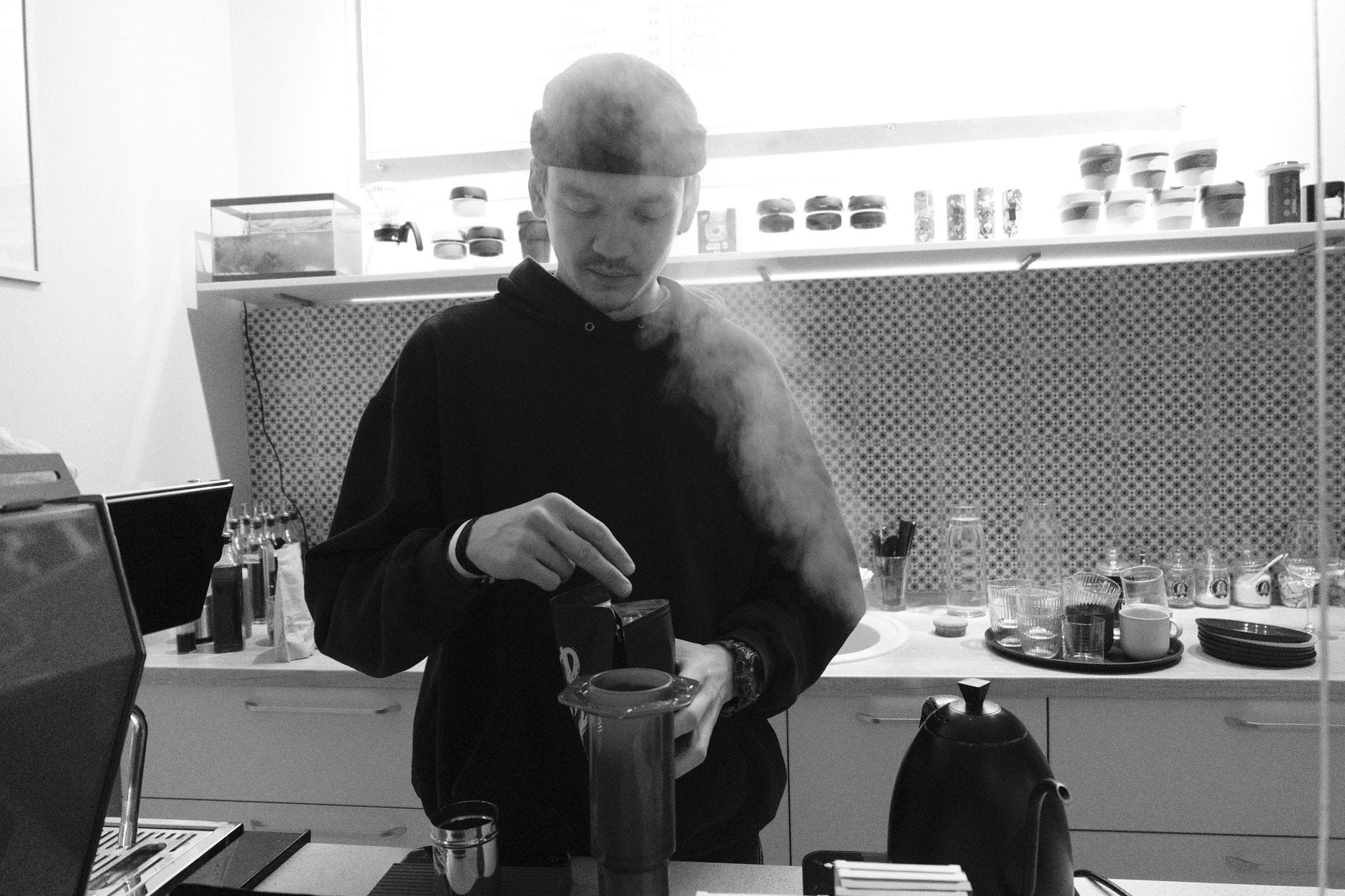 Barista parzy świeżą kawę Aeropressem w nowoczesnej kuchni